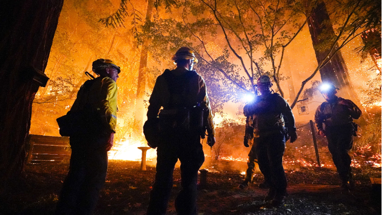 Firefighters make a stand in the backyard of a home in front of the advancing CZU August Lightning Complex Fire Friday, Aug. 21, 2020, in Boulder Creek, Calif. (AP Photo/Marcio Jose Sanchez)