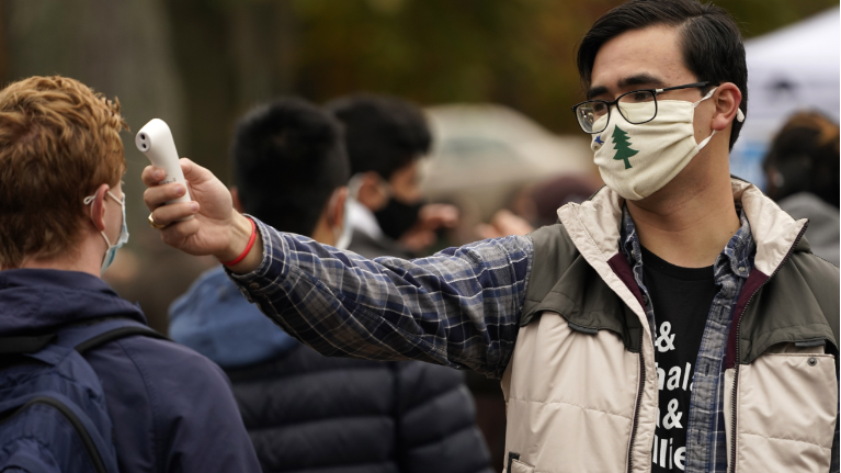 Alex Mukai checks the temperature of a man in line to attend a campaign event for Sara Gideon, Democratic candidate for U.S. Senate, to help prevent the spread of the coronavirus at the Town Mall, Thursday, Oct. 29, 2020, in Brunswick, Maine. Gideon, the speaker of the Maine House, is challenging incumbent Republican Sen. Susan Collins. (AP Photo/Robert F. Bukaty)